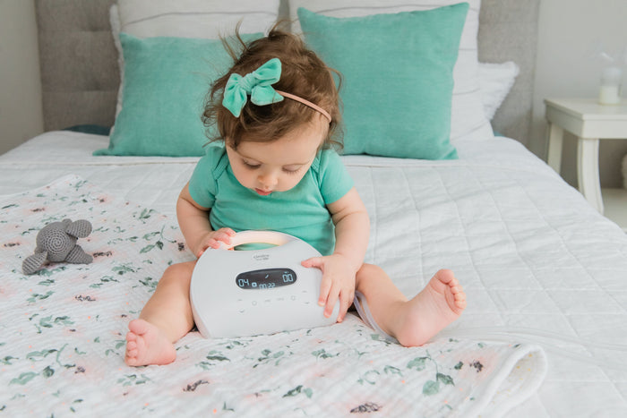 Baby is holding and looking at the Cimilre S7 breast pump