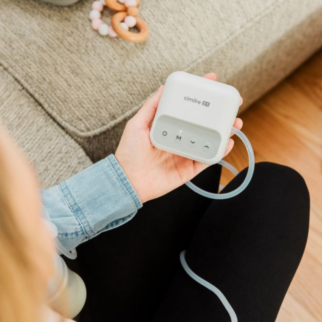 e1 in moms hand with baby toy on the couch in the background