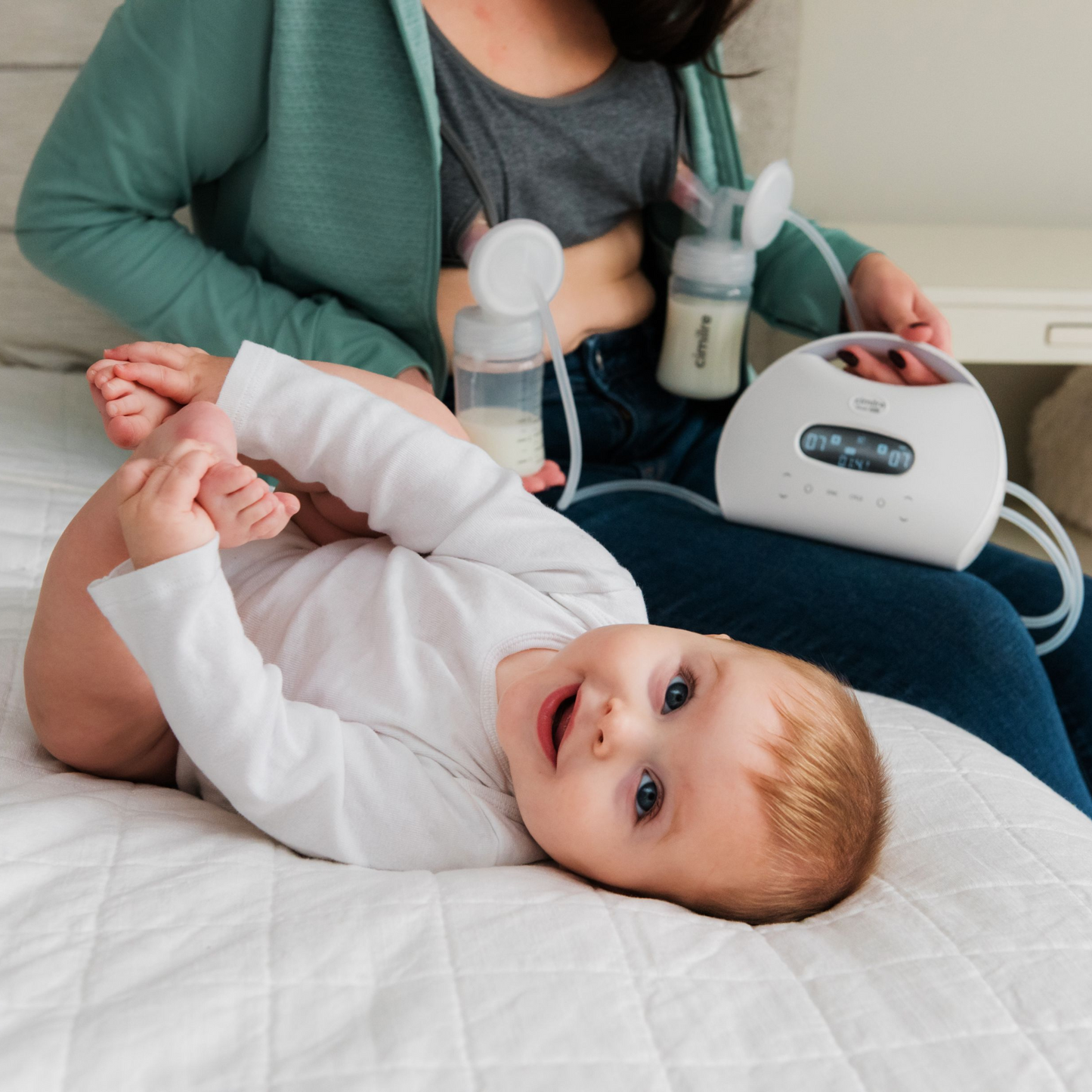 cimilre s7 dual pro in background with mom pumping and baby on bed in foreground