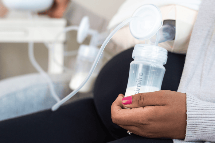 Parent holding a cimilre collection bottle while pumping breast milk