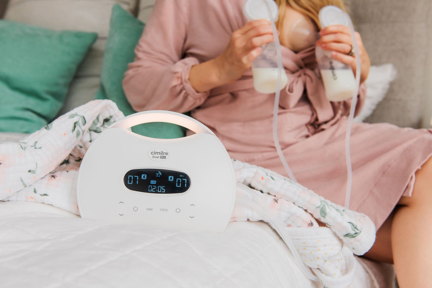 mom sitting on bed with a robe, pumping with the S7 dual pro