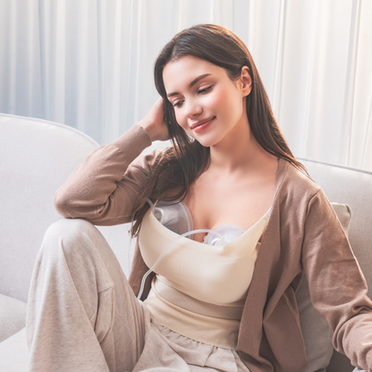 person sitting on a couch pumping with Cimilre hands free collection cups