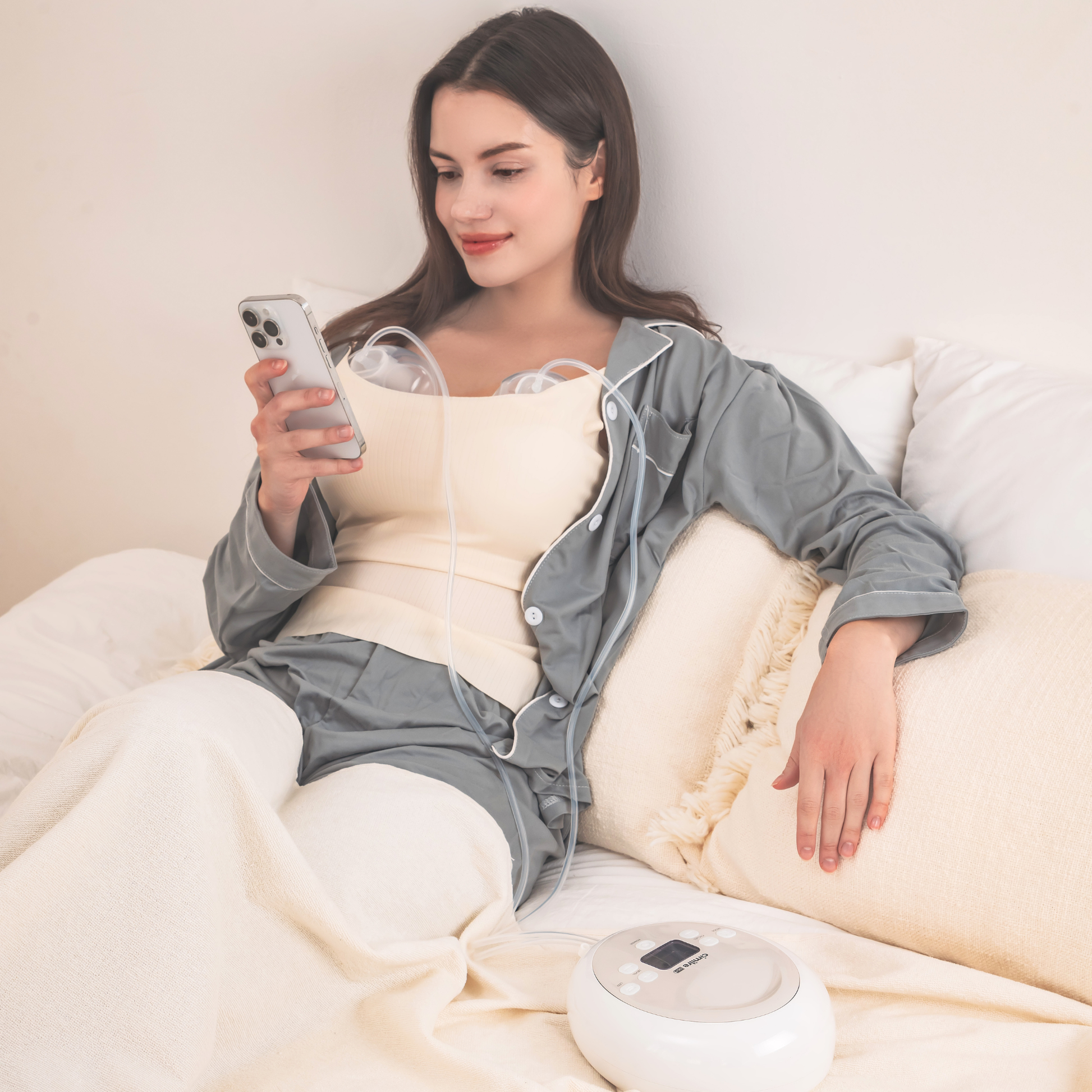 woman in bed pumping with the Cimilre hands free collection cups and S6+ looking at her phone