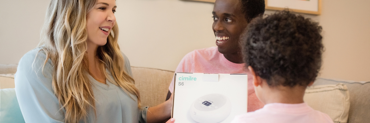 mom holding the box to a breast pump with family supporting